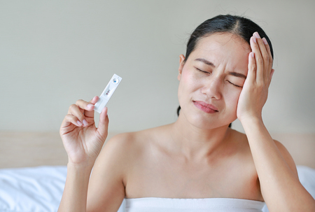 worried young woman with a pregnancy testの写真素材