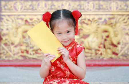 Smiling little Asian girl holding gold envelope during chinese new year festival.の写真素材