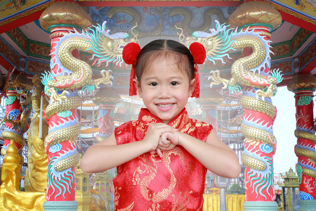 Little chinese girl in traditional Chinese cheongsam blessing for you in chinese new year festival.の写真素材