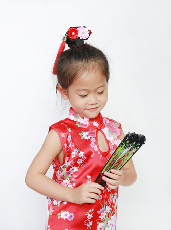 Asian child girl holding Chinese style fan on white background during Chinese new year festival.の写真素材