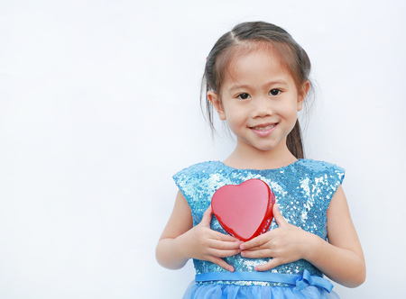 Cute little child girl holding red heart gift box for Valentine's Day isolated on white background.の写真素材