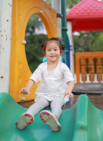 Close up portrait of happy smiling kid girl playing slider on playgroundの写真素材
