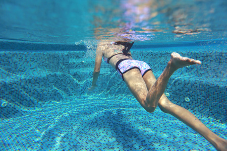 Underwater shot of young woman diving into the swimming pool.の写真素材