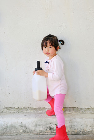 Little farmer girl holding milk bottle in farmの写真素材