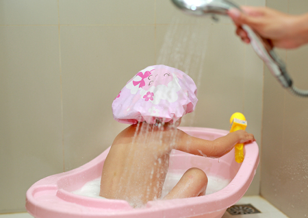 Little child in a cap of foam in bathの写真素材
