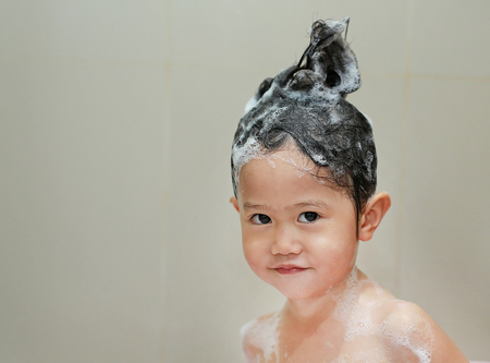 Little girl bathing and washing hair in bubble bath.の写真素材
