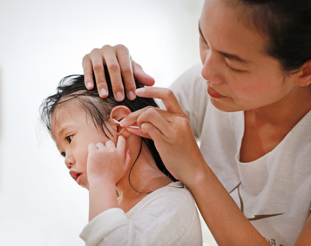 Baby care after bathing (mother cleaning kid's ear)