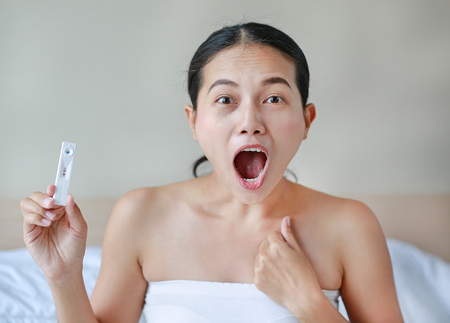 Excited young woman holding positive pregnancy test.の写真素材