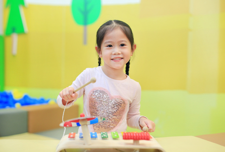 Asian kid girl having fun with Toys, musical instruments