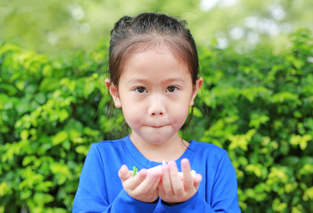 Asian child girl holding some thai sugar and fruit toffee with colorful paper wrapped in her hands. Focus at candy in her handsの写真素材