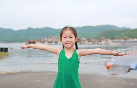 Happy little Asian kid girl Stretch arms and relaxes in hillsideの写真素材
