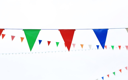 Colorful triangular Flags Hanging in the white sky outdoorの写真素材