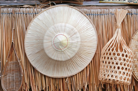 Thai traditional farmer handcraft hat hang on straw wall backgroundの写真素材
