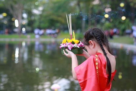 Loy Krathong festival, Asian Child girl in Thai traditional dress with holding krathong for forgiveness Goddess Ganges to celebrate festival in Thailand.の写真素材