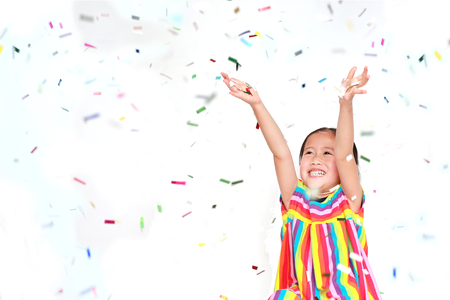 Happy little child girl with colorful confetti on white background. Happy New Year or Congratulation Concept.の写真素材