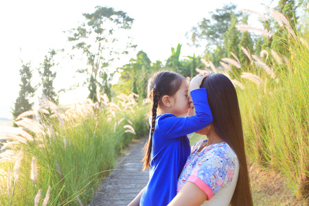 Portrait of Asian daughters nice smell her mother in meadow field at morning sunrise.の写真素材