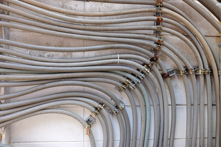 Many wires pipe running on concrete wall.の写真素材