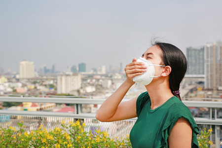Young Asian woman wearing a protection mask against PM 2.5 air pollution in Bangkok city. Thailand....