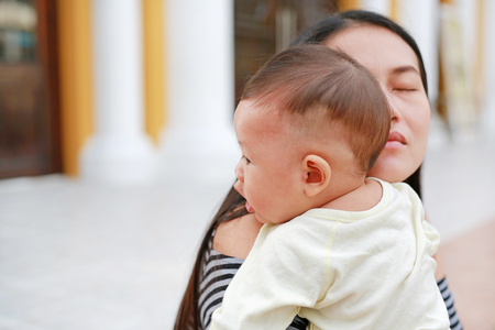 Asian mother carrying her infant. Close-up.の写真素材