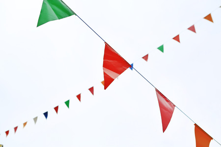 Colorful triangular Flags Hanging in the white sky outdoor.の写真素材