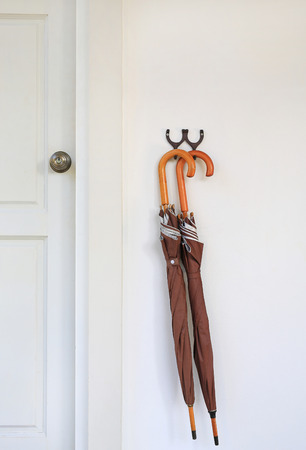 Umbrellas hanging in front of wood door room. Ready to be picked up during rain.の写真素材