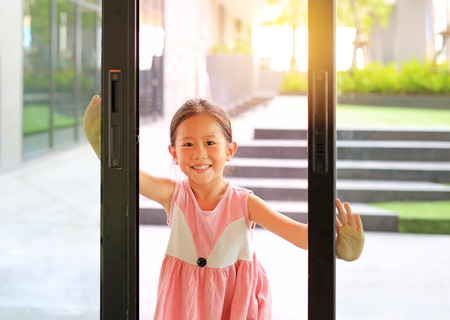 Little Asian children open glass door in front of the living room.の写真素材