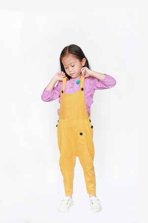 Little Asian child girl wearing a yellow dungarees isolated on white background.の写真素材