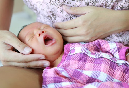 Newborn baby boy  yawning on mother lap.の写真素材