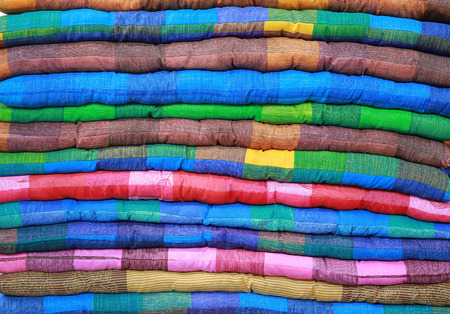 Multicolored stack of seat cushions.