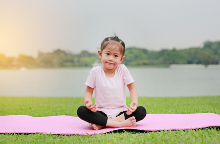 Portrait of little asian child girl doing yoga in the public park.の写真素材