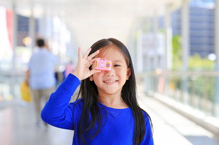 Beautiful smiling Asian little girl taking photo by toy camera to take pictures outdoor. Kid development concept.の写真素材