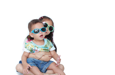 Portrait little Asian sister embracing little brother wearing a flowers summer dress and sunglasses isolated on white background. Summer and fashion concept.の写真素材