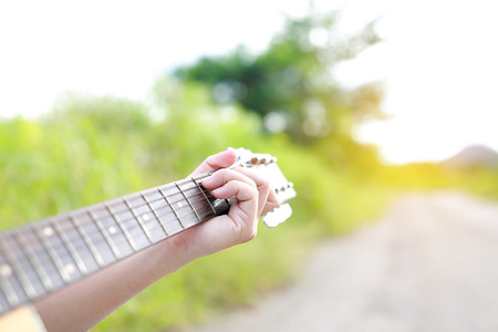 Close-up male hands playing on acoustic guitar in the nature.
