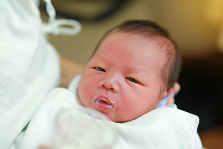 Infant baby feeding milk from glass cup.の写真素材