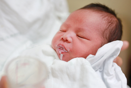 Mother feeding milk infant baby by glass cup.の写真素材