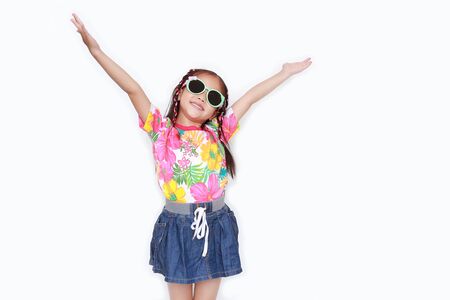 Happy little Asian kid girl stretch arms wide open wearing a floral pattern summer dress and sunglasses isolated on white background. Summer and fashion concept.の写真素材