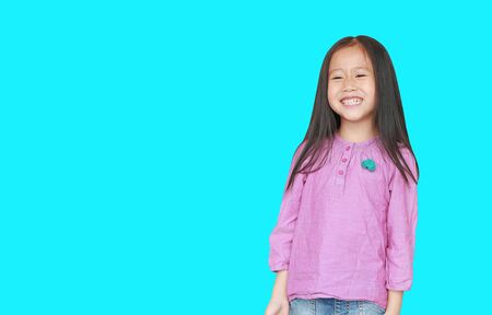 Portrait of happy little Asian child girl isolated on Cyan background with copy space. Kid smiling concept.の写真素材