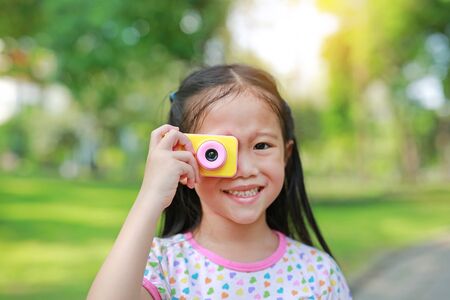 Portrait of happy little girl with digital camera toy in the garden outdoor.の写真素材