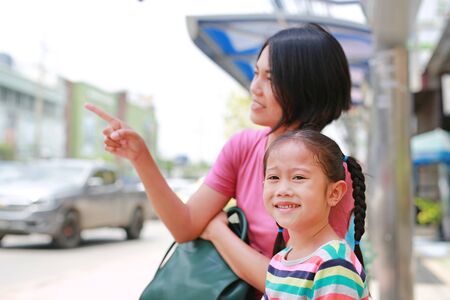 Asian mom and her daughter sitting on public transport bus. Mom pointing something to child girl looking.の写真素材