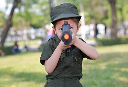Asian child girl in pilot soldier suit costume with shooting gun up. Dream job concept.