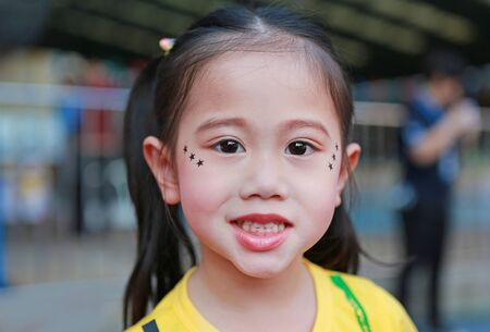 Portrait of Asian child girl with makeup and sticking on face sequins in the form of stars.の写真素材