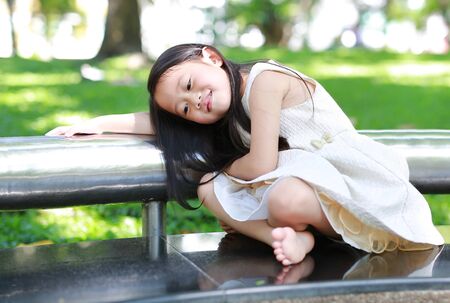 Portrait of smiling little Asian child girl in sunny green park.の写真素材