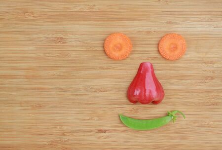 Happy face with fruit and vegetables on wooden background.の写真素材