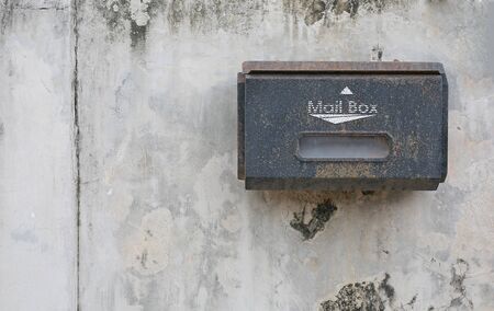 Old red mailbox mounted on a cement wall with copy space.の写真素材