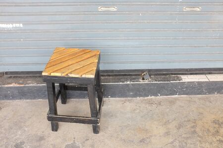Wooden stool in front of metal door.