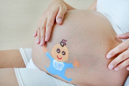 Close up Big tummy of Pregnant woman painted happy babyの写真素材