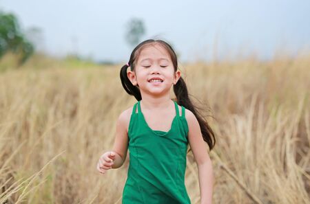 Happy little child girl relaxing in summer field outdoor.の写真素材