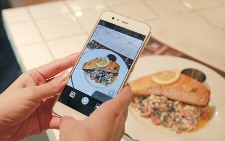 Woman hands using smartphone taking photo of Grilled salmon steak.の写真素材