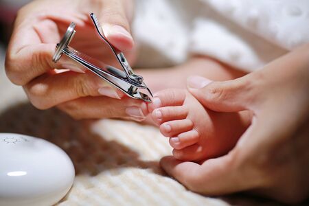 Close up mother hands cutting baby toenails. Baby care concept.の写真素材