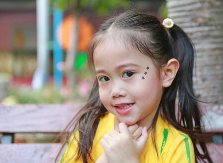 Portrait of Asian child girl with makeup and sticking on face sequins in the form of stars.の写真素材
